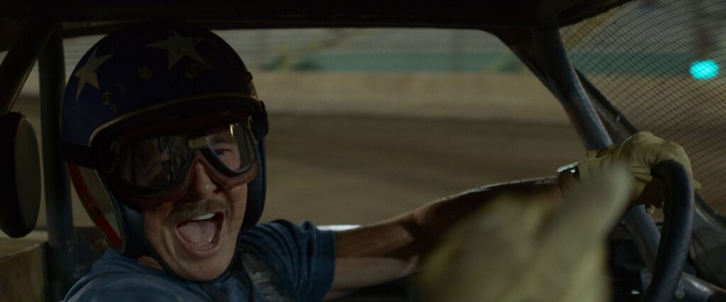 Brad Pitt con casco de especialista conduciendo un coche de carreras