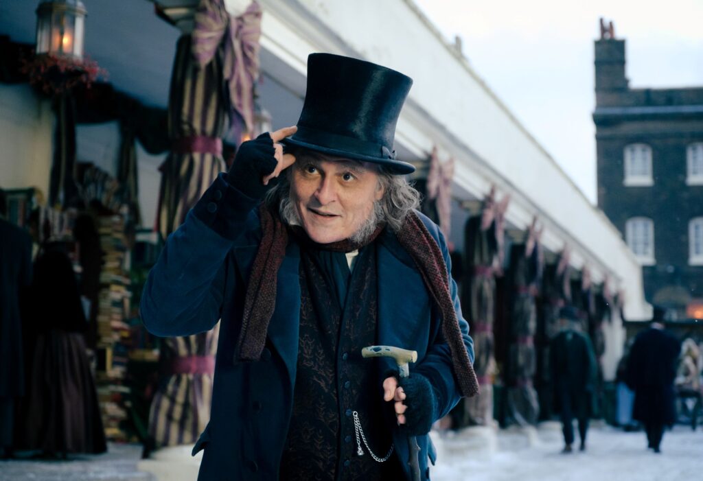 Johnny Depp caracterizado como Ebenezer Scrooge con sombrero de copa en una calle nevada