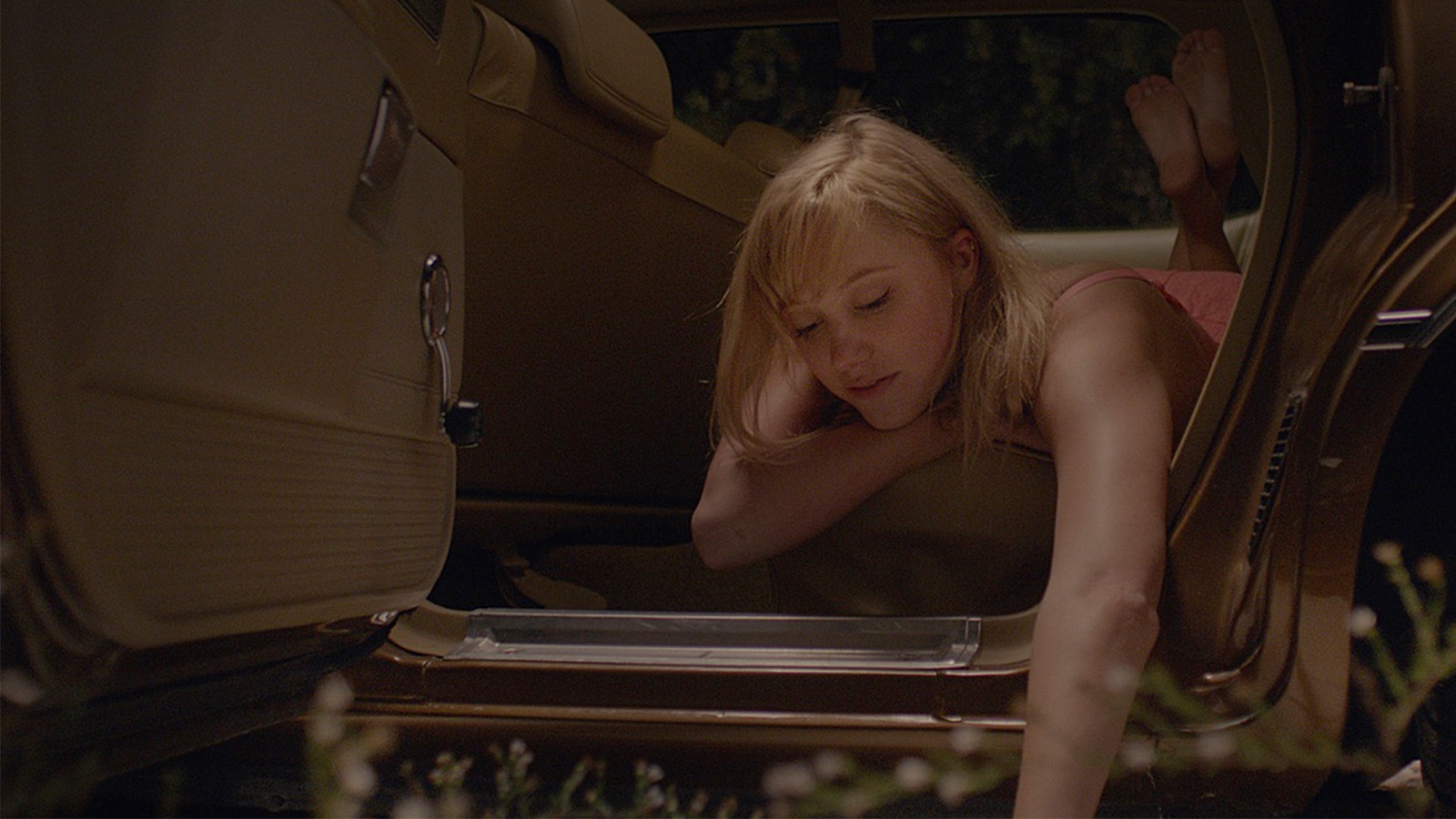 Maika Monroe tumbada en un coche en It Follows