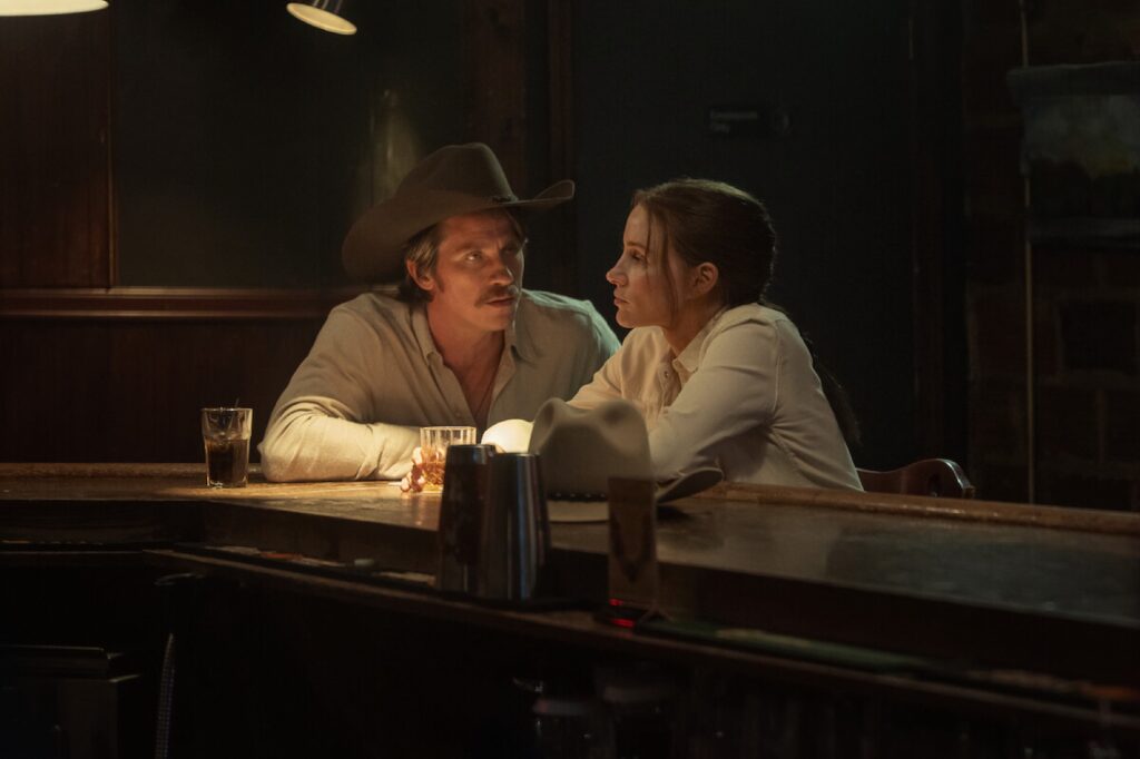 Jessica Chastain conversa en la barra de un bar en penumbra con un hombre con sombrero vaquero en Heartland