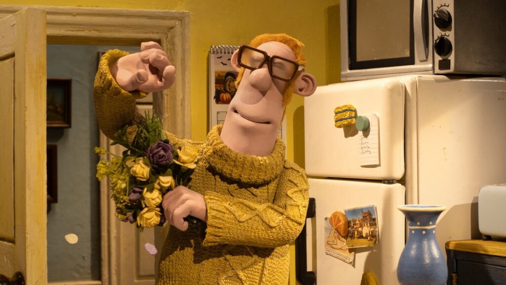 El Granjero, con jersey mostaza y gafas, sostiene un ramo de flores en la cocina de la granja