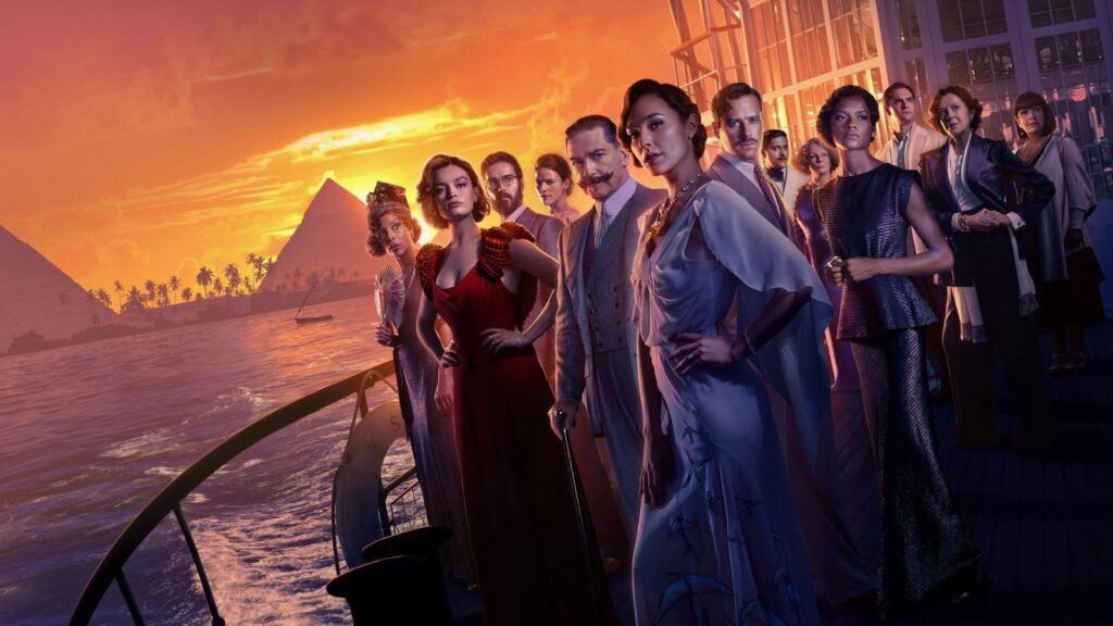 Kenneth Branagh como Poirot y Gal Gadot, con el resto del reparto, en la cubierta de un barco al atardecer en Muerte en el Nilo (2022)