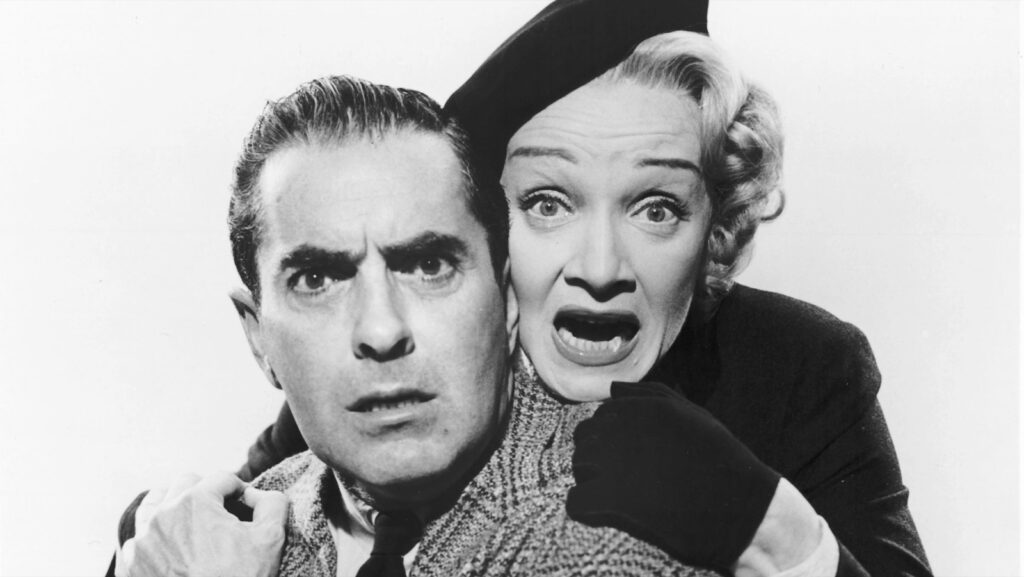 Tyrone Power y Marlene Dietrich, con gesto de sobresalto, en una foto promocional de Testigo de cargo (1957)